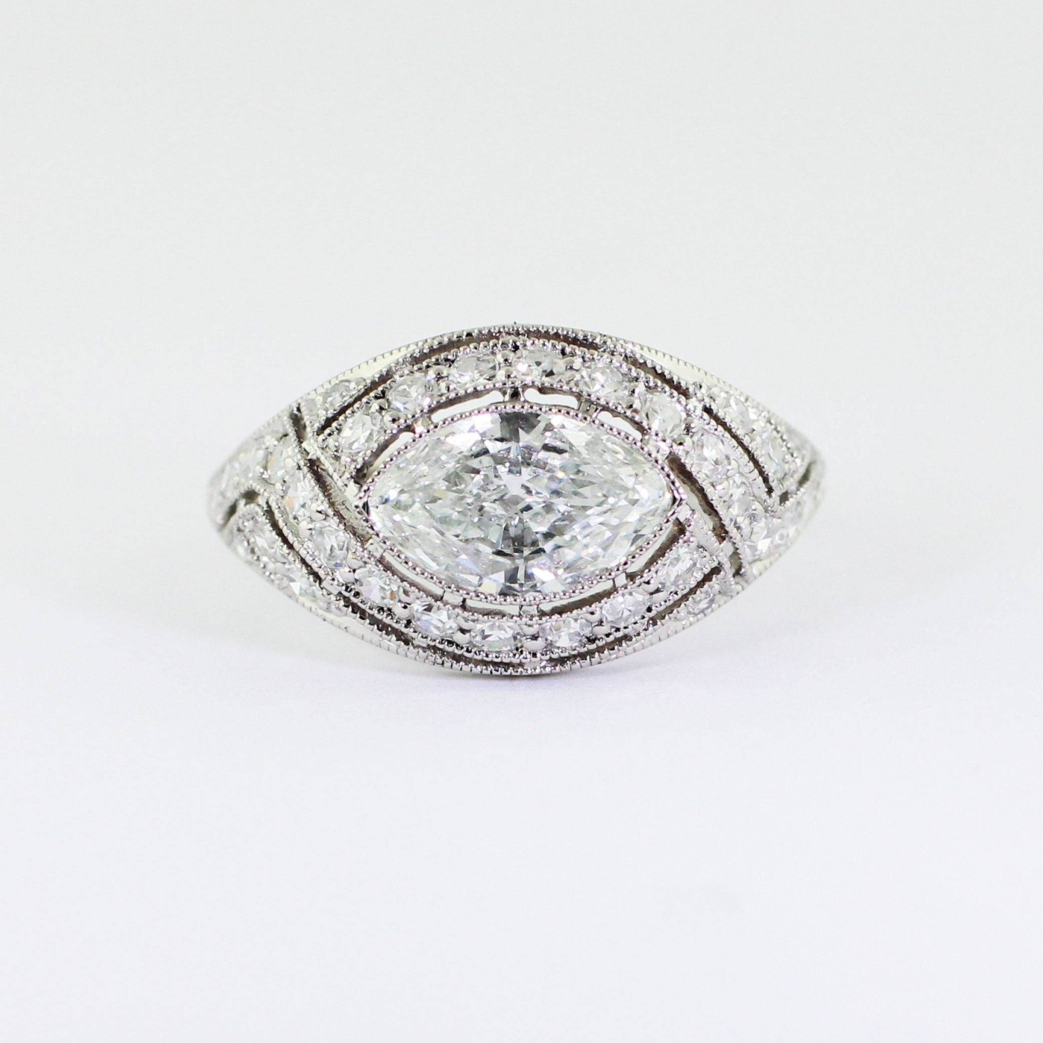 Custom platinum Art Deco ring featuring a marquise center diamond set in an illusion setting with milgrain detailing and bead-set accent diamonds.