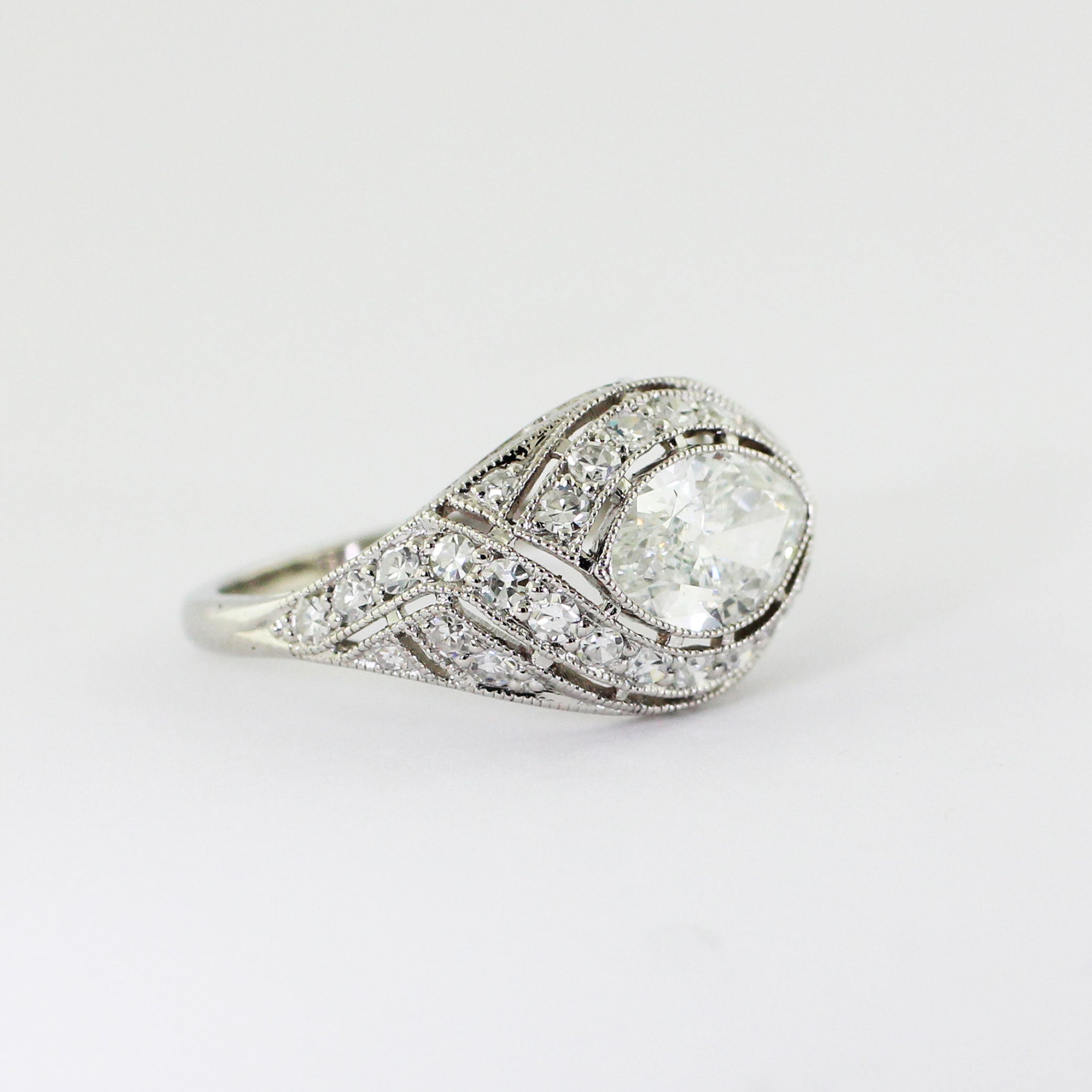Custom platinum Art Deco ring featuring a marquise center diamond set in an illusion setting with milgrain detailing and bead-set accent diamonds.