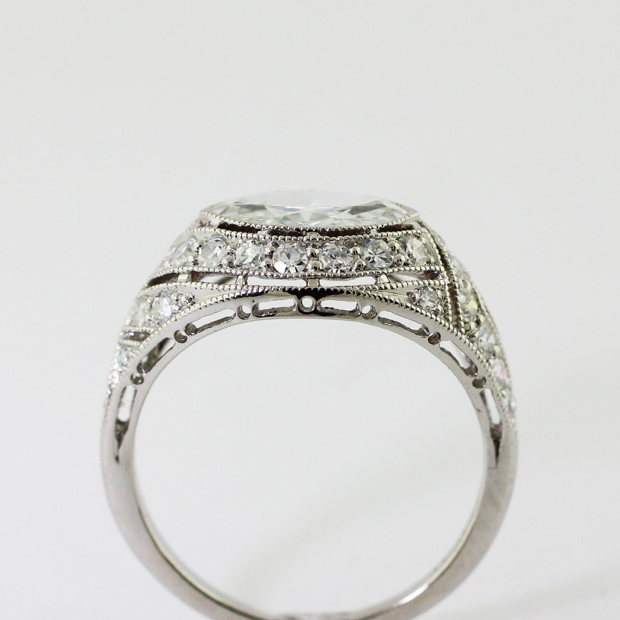 Custom platinum Art Deco ring featuring a marquise center diamond set in an illusion setting with milgrain detailing and bead-set accent diamonds.