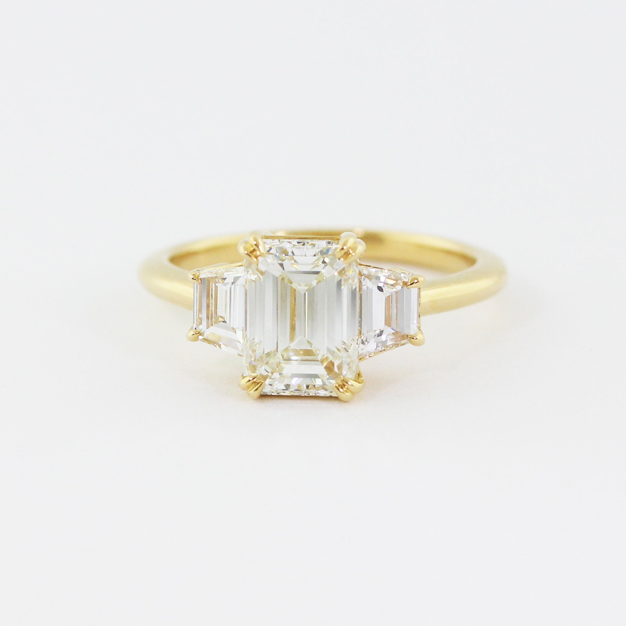 Custom 14k yellow gold three stone engagement ring with an heirloom emerald-cut center diamond flanked by two emerald-cut accent diamonds.