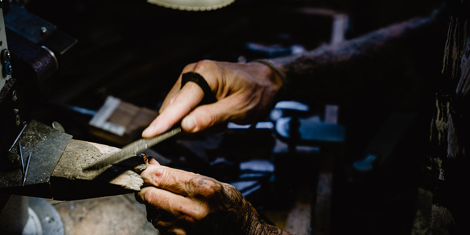 Our jeweler meticulously files a ring, crafting intricate details.