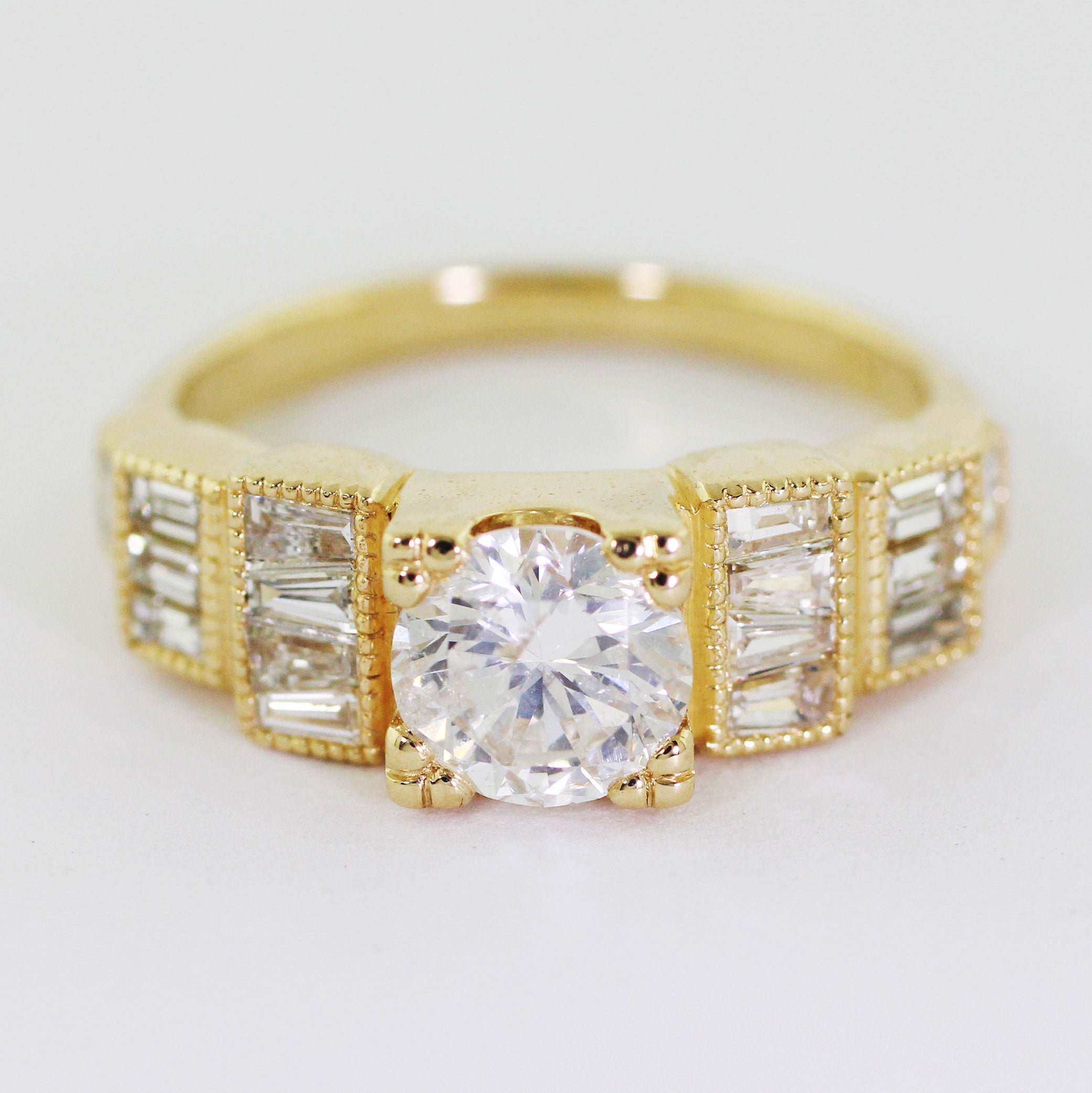 Custom 14k yellow gold Art Deco engagement ring with a prong-set center diamond and a series of heirloom diamonds channel-set along the band in a step-down pattern