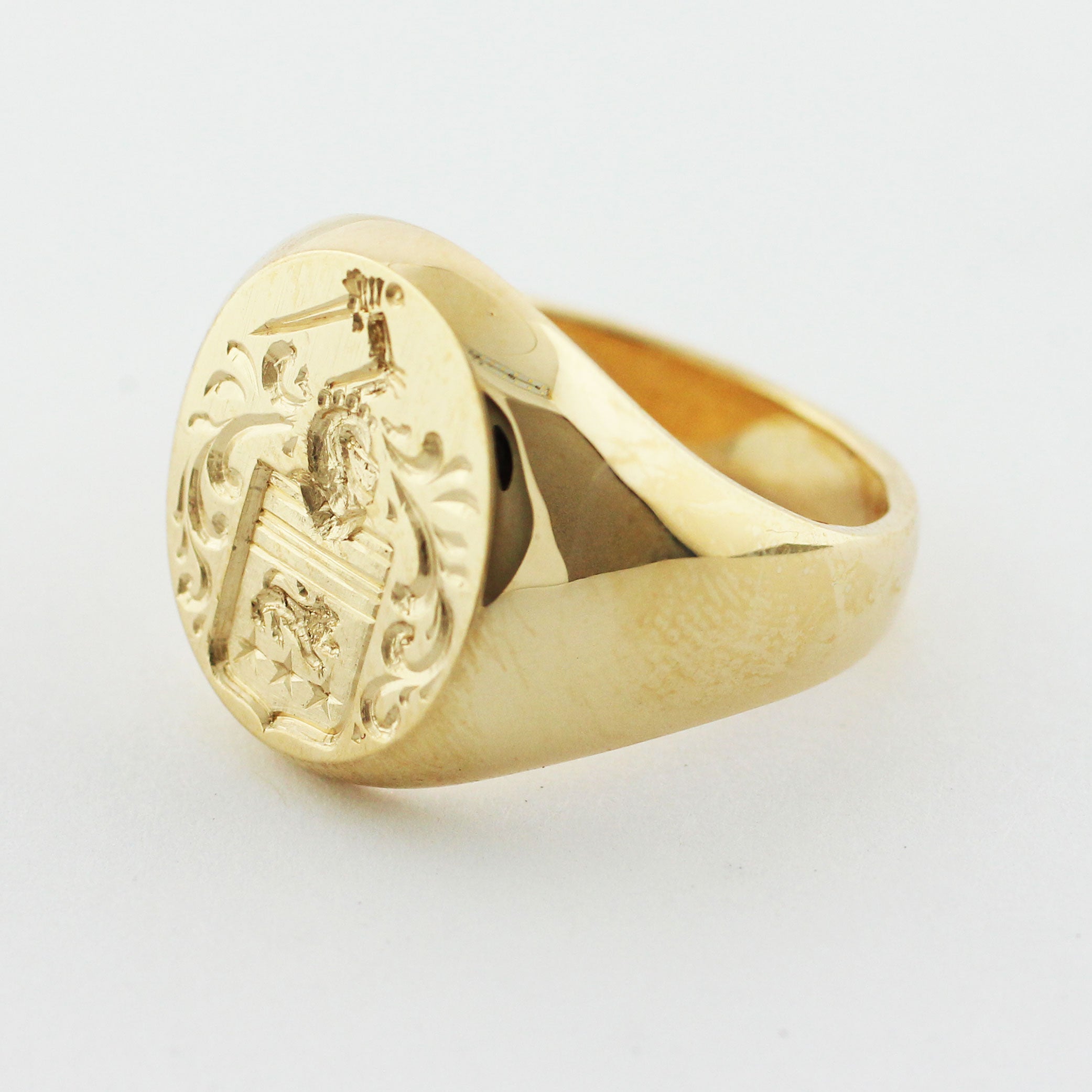 custom 14-karat yellow gold signet ring proudly displays a meticulously crafted intaglio family crest
