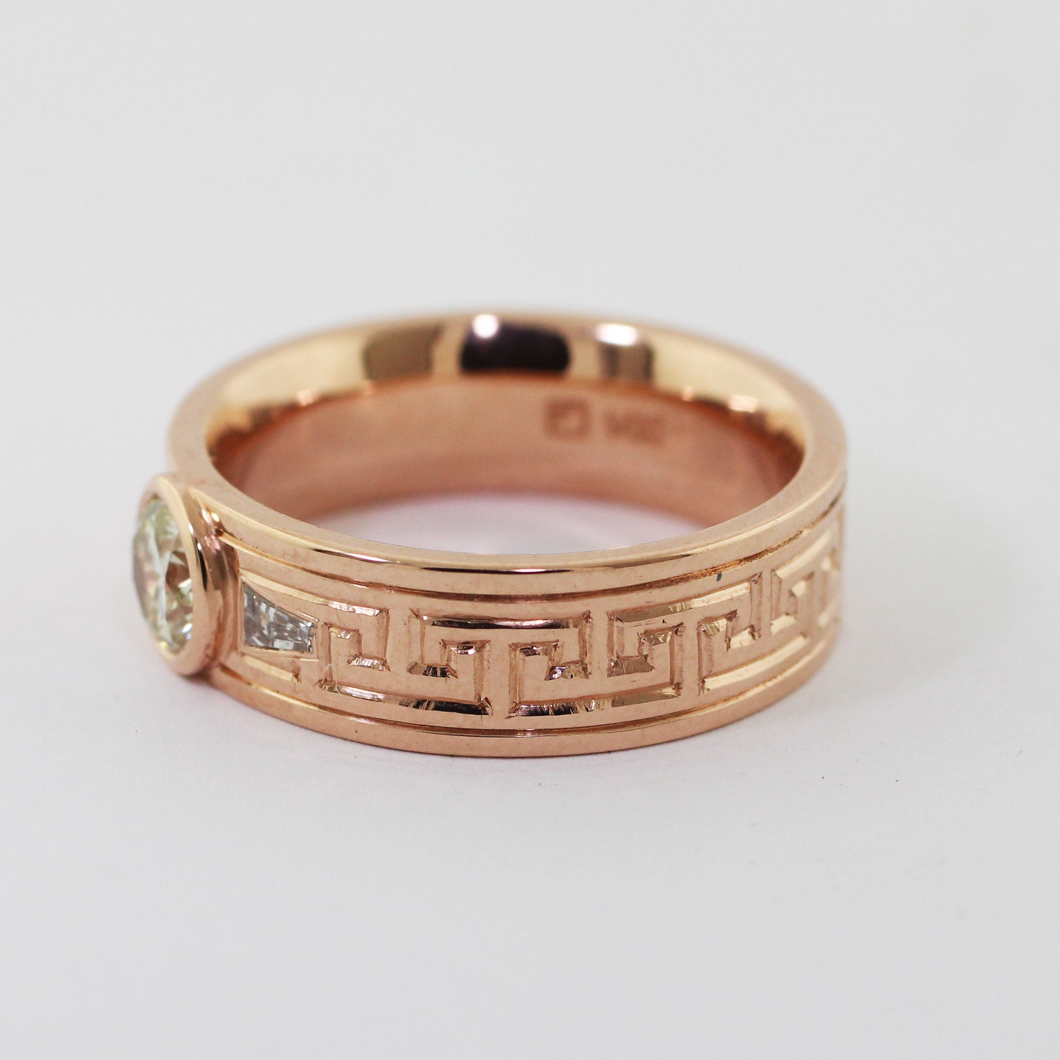Crafted from 14kr gold and utilizing heirloom diamonds this custom men's ring features a timeless Greek key pattern expertly engraved on the exterior. Two tapered baguettes are set on either side of the center diamond.