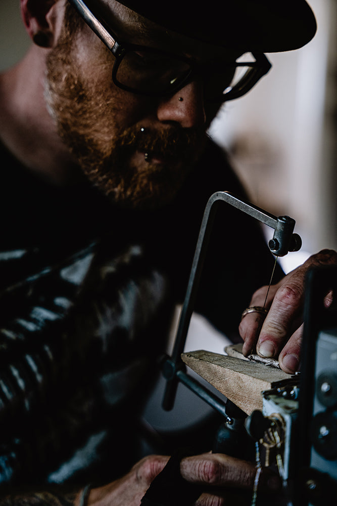 Our jeweler skillfully saws through metal with precision and focus.
