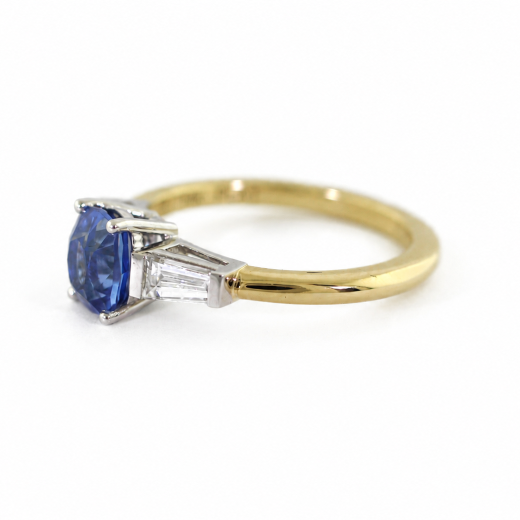 The Rainbolt ring with a cushion cut blue sapphire center stone and tapered baguette side stones in a classic basket setting.