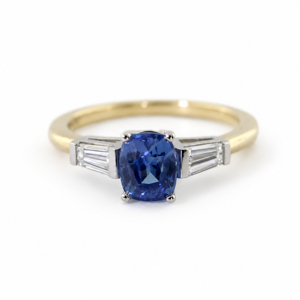 The Rainbolt ring with a cushion cut blue sapphire center stone and tapered baguette side stones in a classic basket setting.
