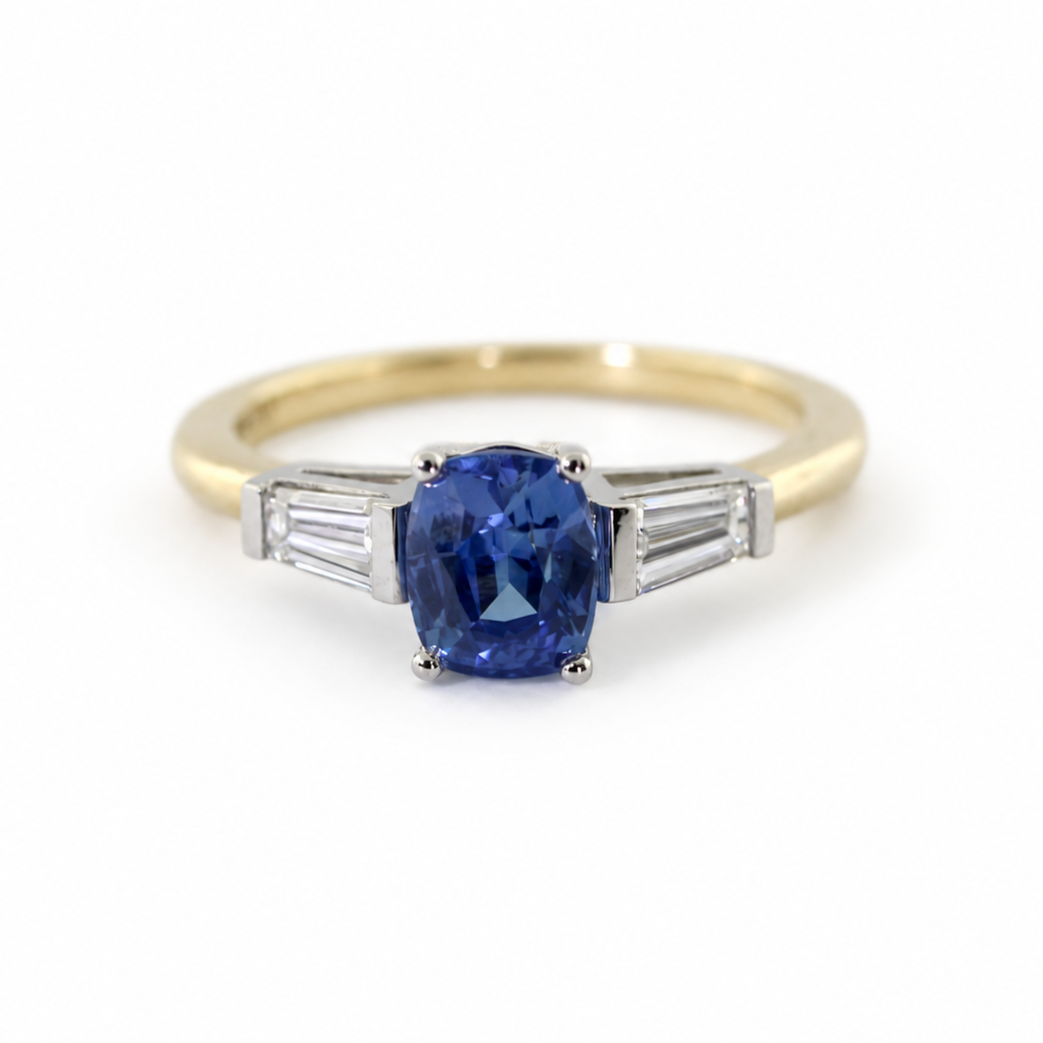 The Rainbolt ring with a cushion cut blue sapphire center stone and tapered baguette side stones in a classic basket setting.