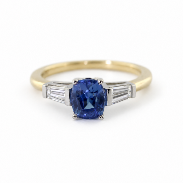 The Rainbolt ring with a cushion cut blue sapphire center stone and tapered baguette side stones in a classic basket setting.