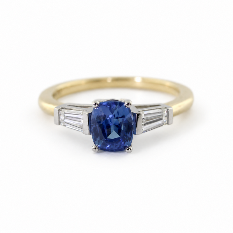 The Rainbolt ring with a cushion cut blue sapphire center stone and tapered baguette side stones in a classic basket setting.