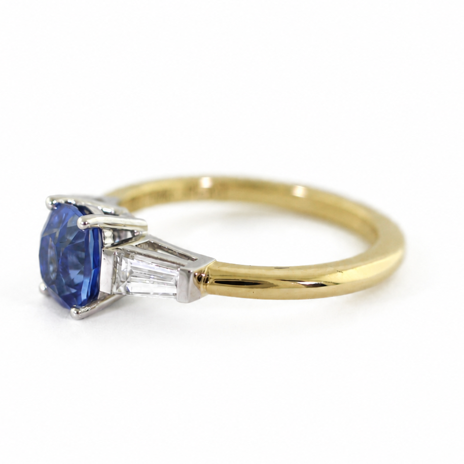 The Rainbolt ring with a cushion cut blue sapphire center stone and tapered baguette side stones in a classic basket setting.
