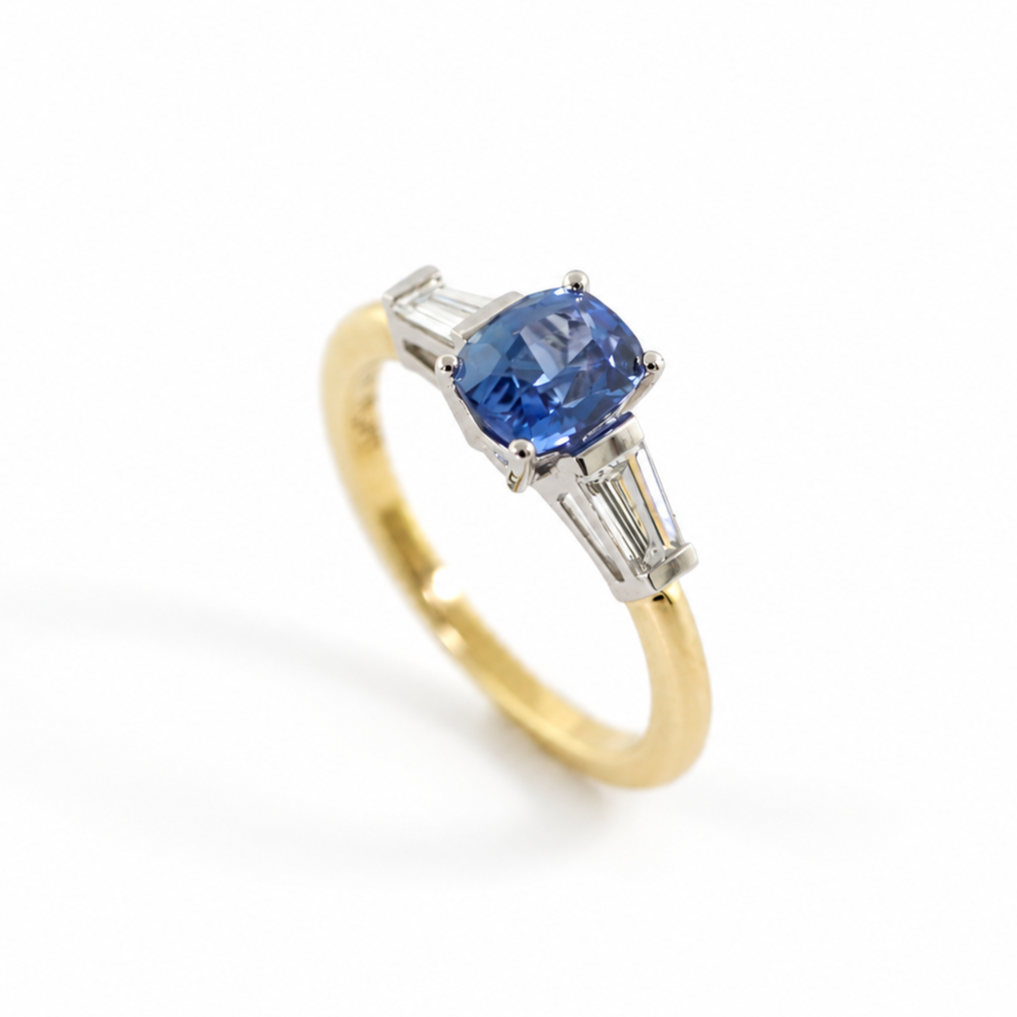 The Rainbolt ring with a cushion cut blue sapphire center stone and tapered baguette side stones in a classic basket setting.
