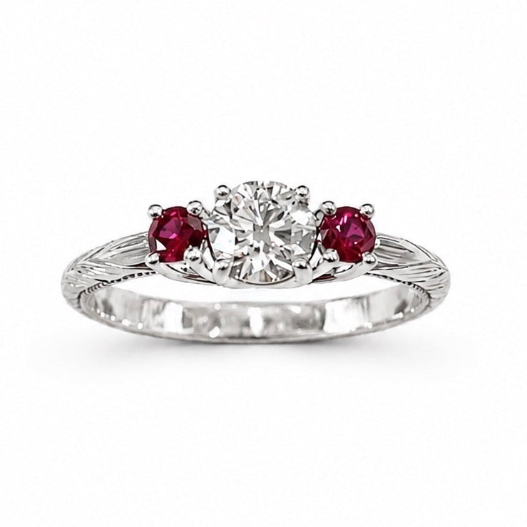 Evangeline platinum trellis ring with a 3/4 carat round brilliant diamond, pigeon blood ruby side stones, hand engraving, and milgrain rail.