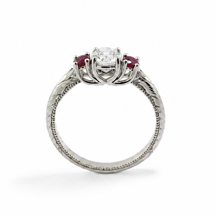 Evangeline platinum trellis ring with a 3/4 carat round brilliant diamond, pigeon blood ruby side stones, hand engraving, and milgrain rail.