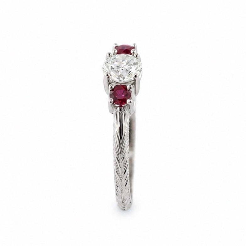 Evangeline platinum trellis ring with a 3/4 carat round brilliant diamond, pigeon blood ruby side stones, hand engraving, and milgrain rail