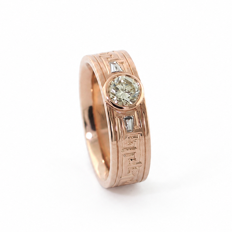 Peterman diamond ring with a round brilliant cut center stone, baguette side stones, and hand-engraved Greek key pattern.